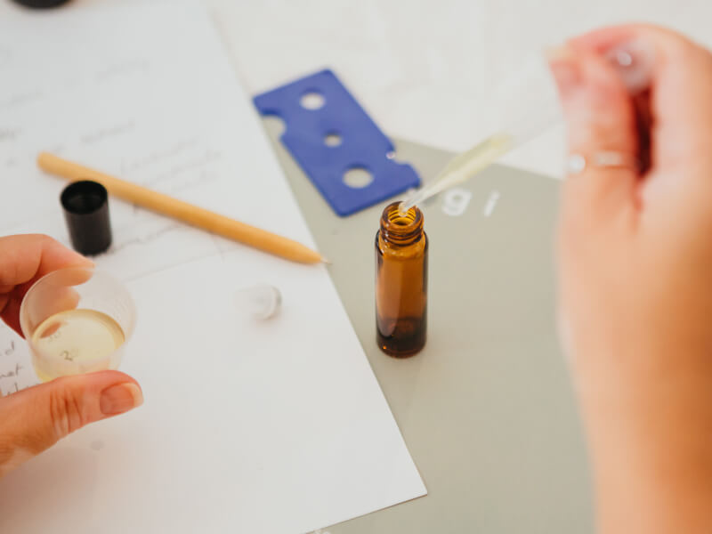 Person adding drops of oil to a small amber vial